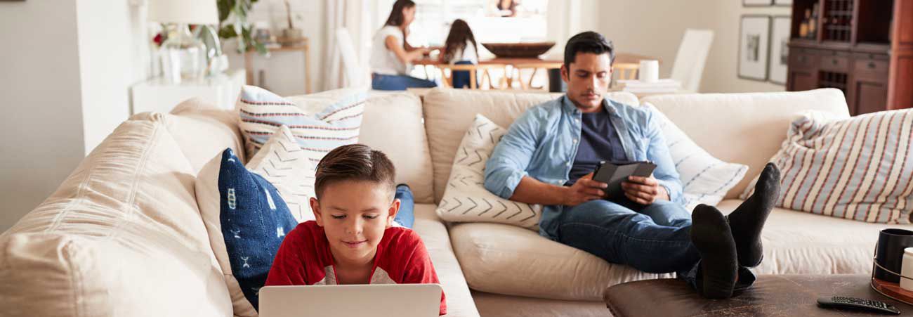 Eine Familie sitzt lesend in ihrem Wohnzimmer
