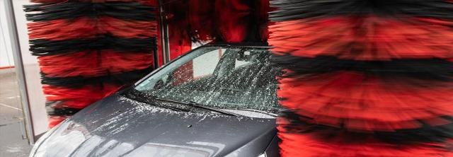 Auto steht zwischen zwei Bürsten in Waschanlage