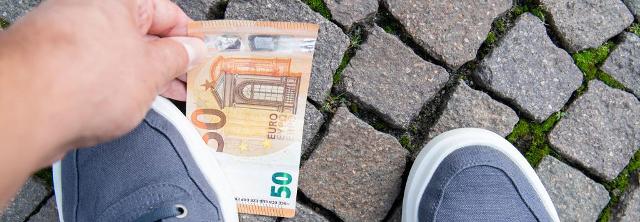 Mann hebt 50-Euro-Schein von Straße auf