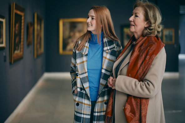 Zwei Frauen im Mantel stehen in einer Gemäldegalerie