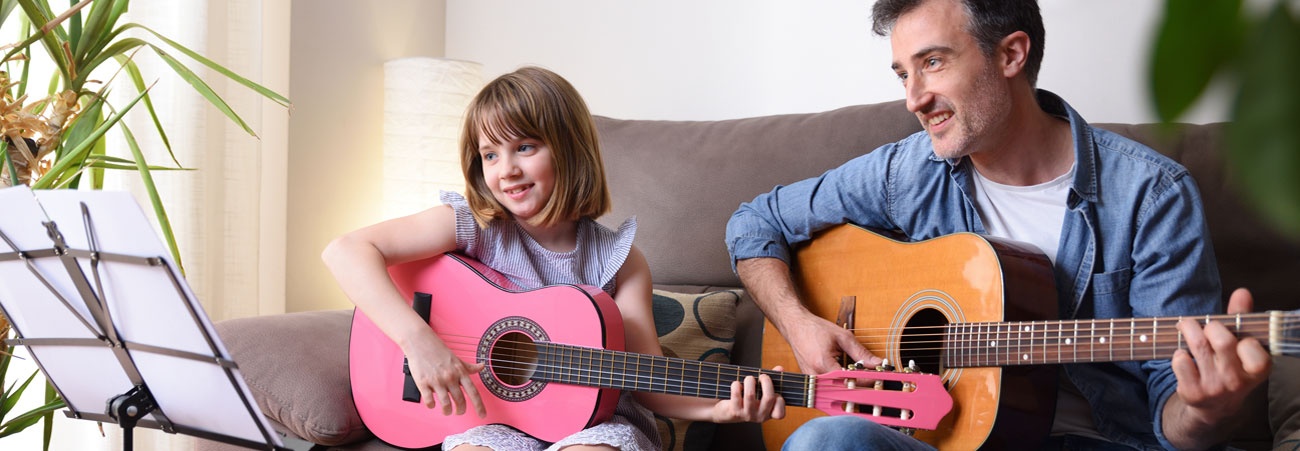 Vater und Tochter spielen im Wohnzimmer Gitarre