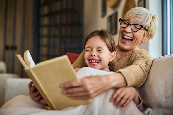 Oma und Enkelin lachen beim Buch lesen