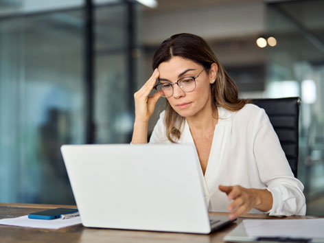 Junge Businessfrau am Schreibtisch in Laptop schauend